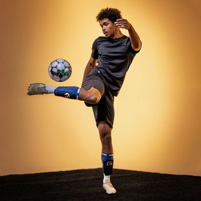 Person kicking a soccer ball against a yellow background