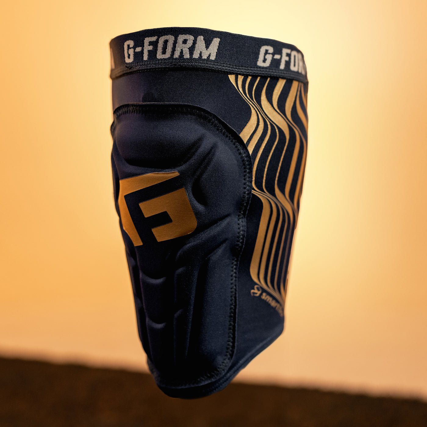 Black and gold G-Form knee pad on a gradient background