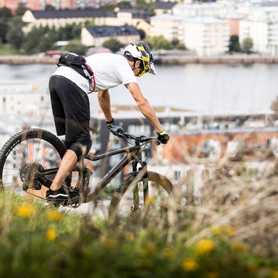 Mountain biker wearing a USWE Zulo Hydration System Waist Pack during a ride on a trail overlooking a cityscape, showcasing the secure fit and lightweight design for active use. | 8Lines Shop